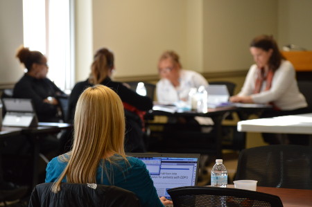 A group of four, and a single woman working in a conference room.