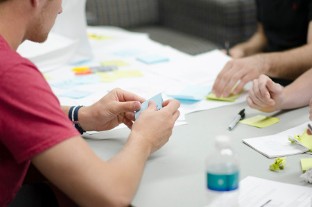 Three sets of hands working at a conference table.